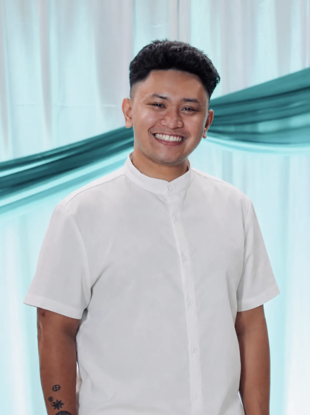 Portrait of Teacher Ian Onno, founder of Tallaro, smiling in a white shirt