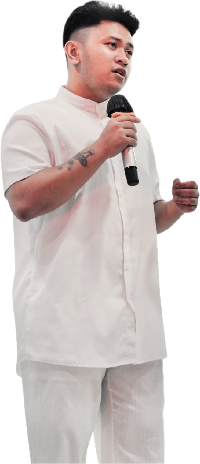 Teacher Ian Onno in white, speaking into a microphone